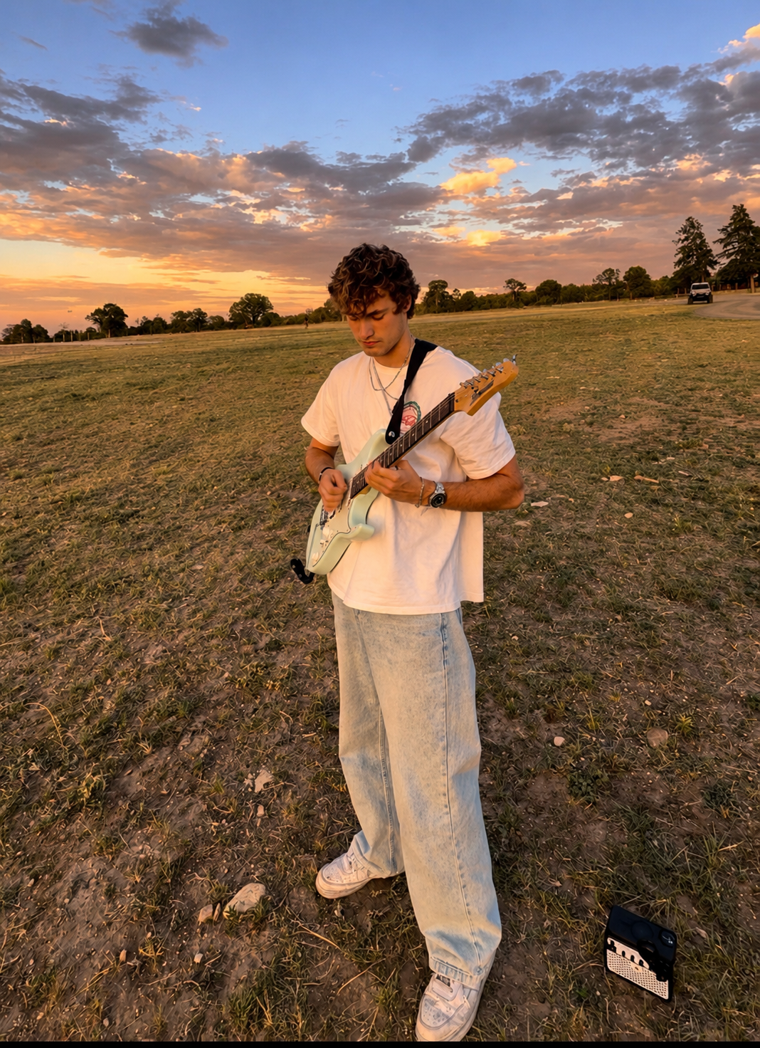 Christian playing electric guitar in a field at sunset